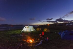 Tente blanche et feu de camp sur une plage sous un ciel étoilé