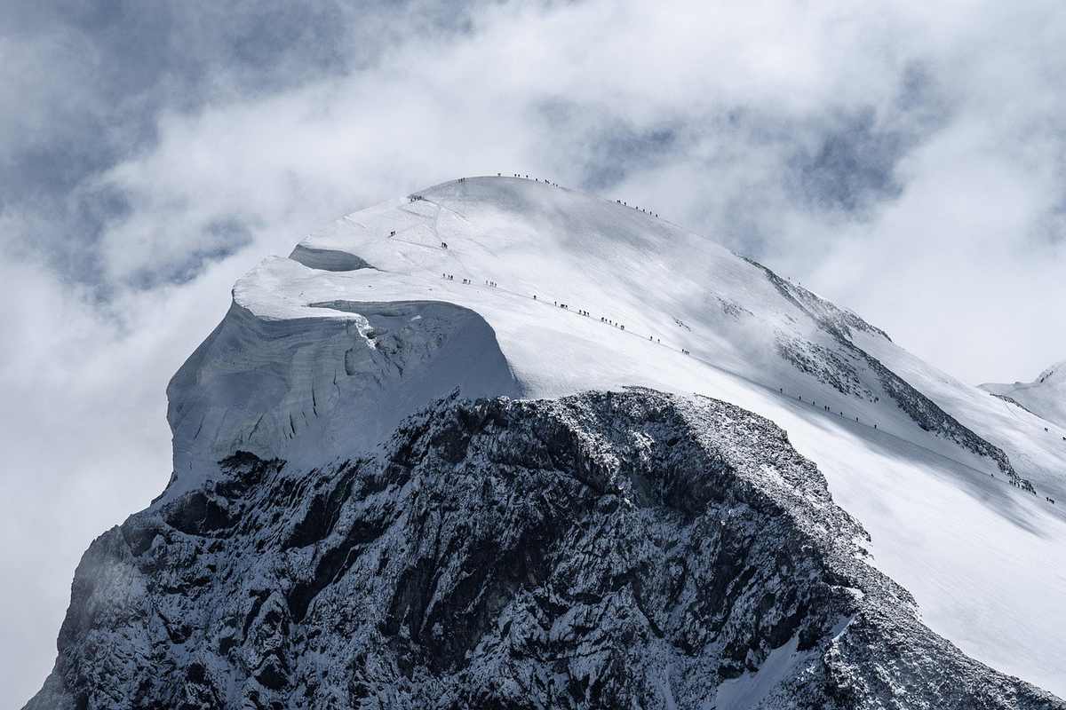 Montagne enneigée sous nuages, face rocheuse visible