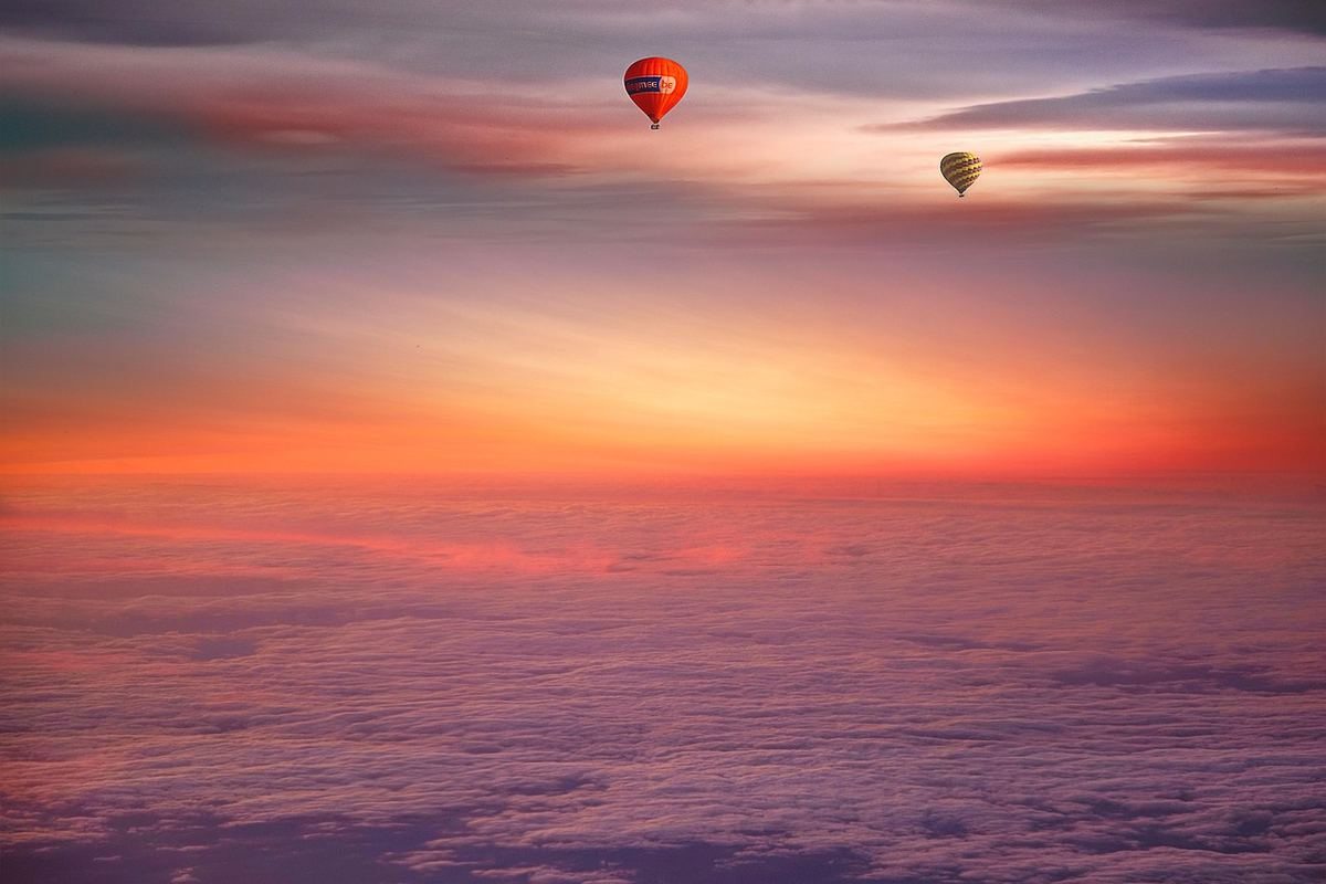 Ballons à air chaud flottant au-dessus de nuages colorés au lever du soleil