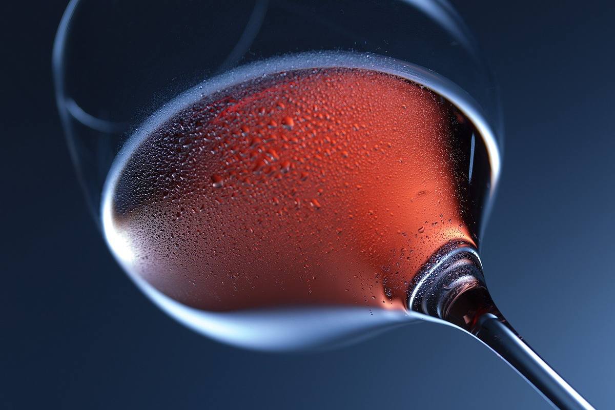 Verre à vin demi-rempli de rosé sur fond sombre