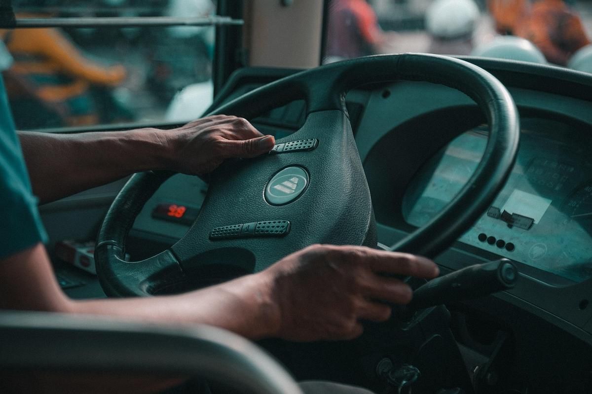 Un conducteur tient le volant avec les deux mains à l'intérieur d'un bus