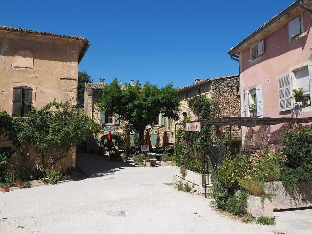 Une rue calme avec maisons en pierre, arbres et café en plein air